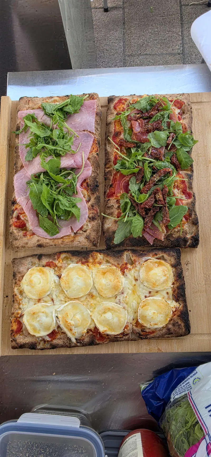 Trois pinsas garnies, posées sur une planche en bois