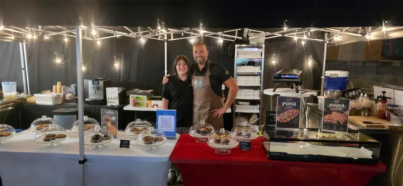 Alexandre et une personne de l’équipe derrière le stand illuminé, le soir