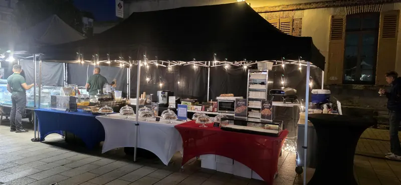 Stand Tendances Gourmandes d’Alex de nuit, sous un barnum noir éclairé de guirlandes